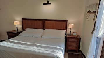 A neatly made bed with white linens, two bedside tables with lamps, and a wooden headboard.