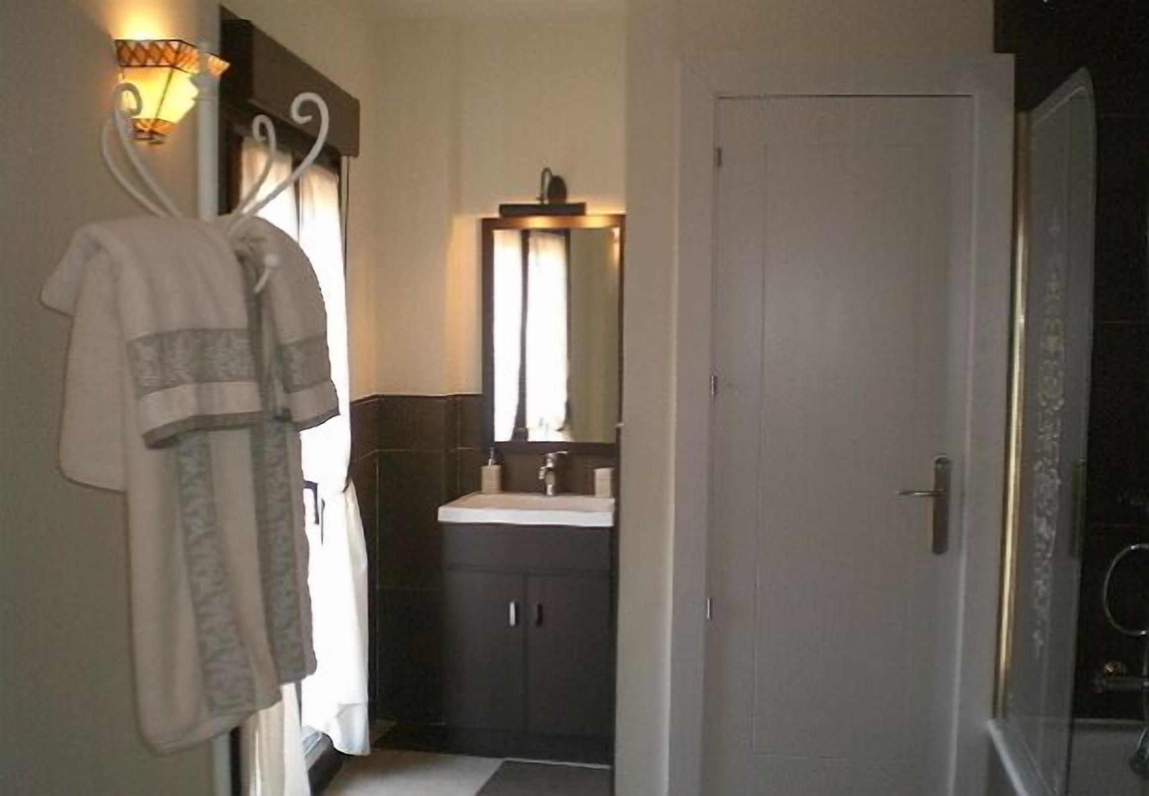 Un baño con lavamanos blanco, armarios oscuros, toallero y espejo.