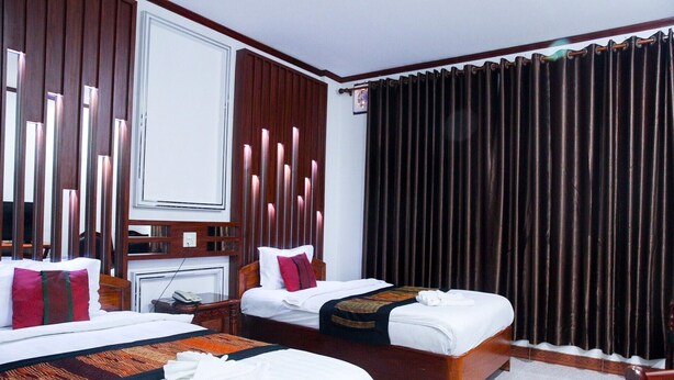 Habitación de hotel con dos camas, un escritorio, un teléfono y una ventana con cortinas oscuras.