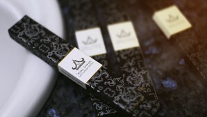 Una corbata negra con etiqueta dorada y etiqueta blanca con texto.