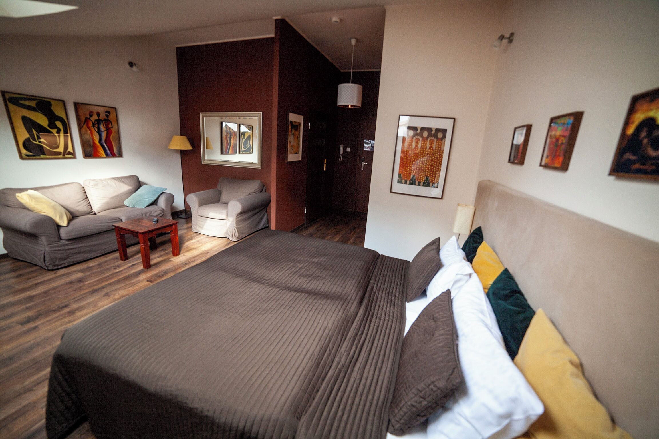 Una moderna camera d'albergo con un letto grande, un divano, un tavolino e opere d'arte alle pareti.