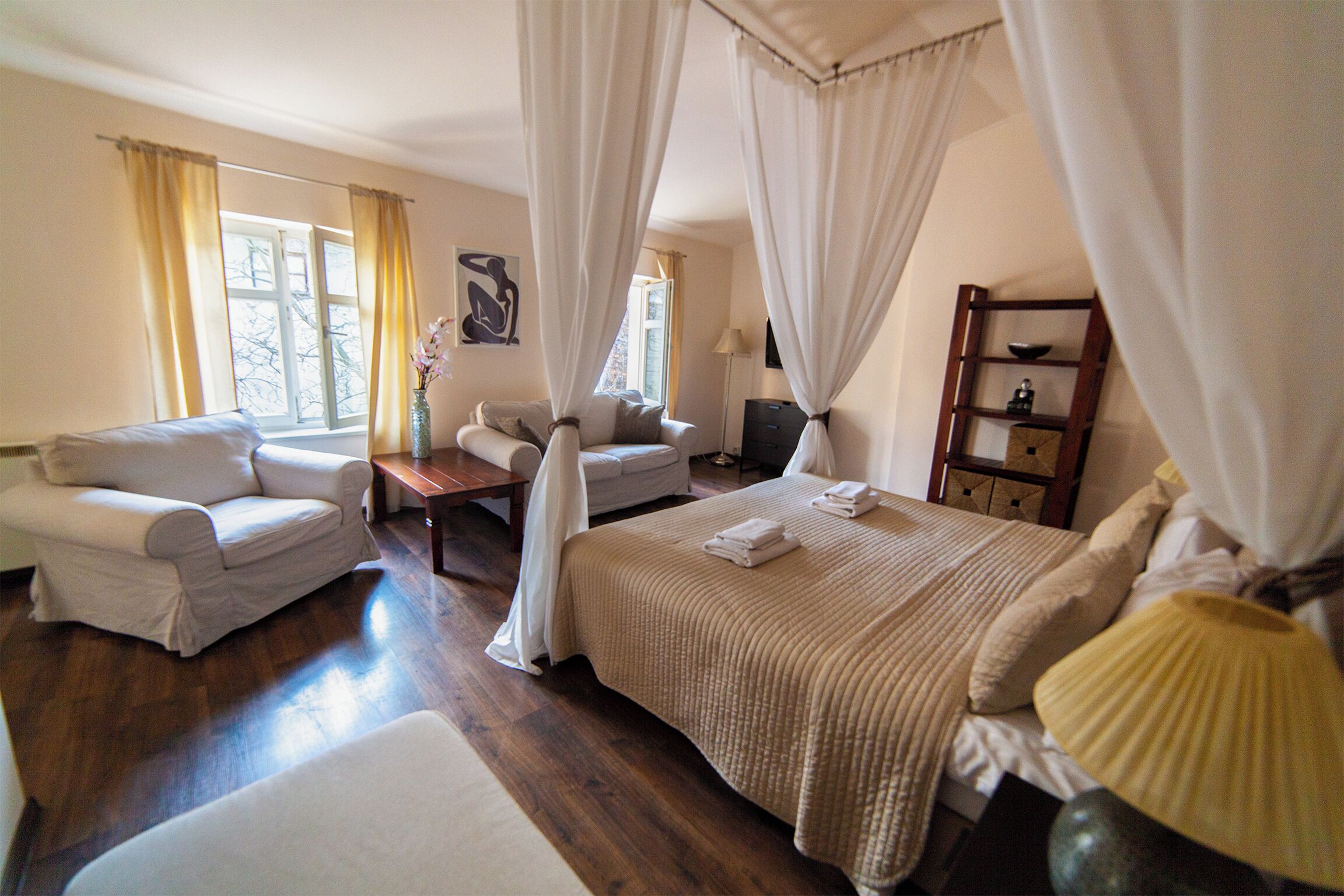 A bedroom with a bed, two armchairs, a nightstand, and a bedside table.