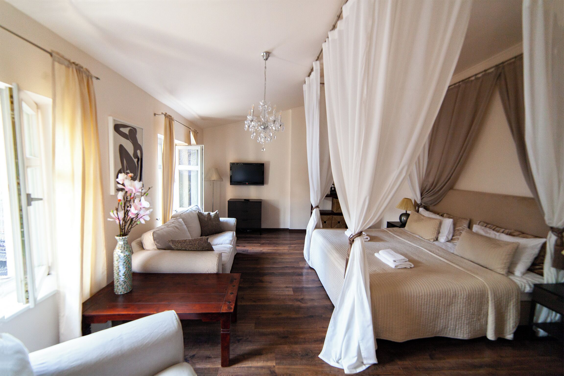 A bedroom with a bed, a sofa, a TV, and a wooden coffee table.