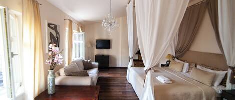 A bedroom with a bed, a sofa, a TV, and a wooden coffee table.