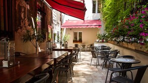 An outdoor patio with a wooden table and chairs, surrounded by potted plants and flowers. - Lounge Apartments (Kraków)