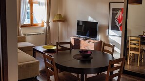 A dining area with a round table, chairs, a television, and a lamp. - Lounge Apartments (Kraków)