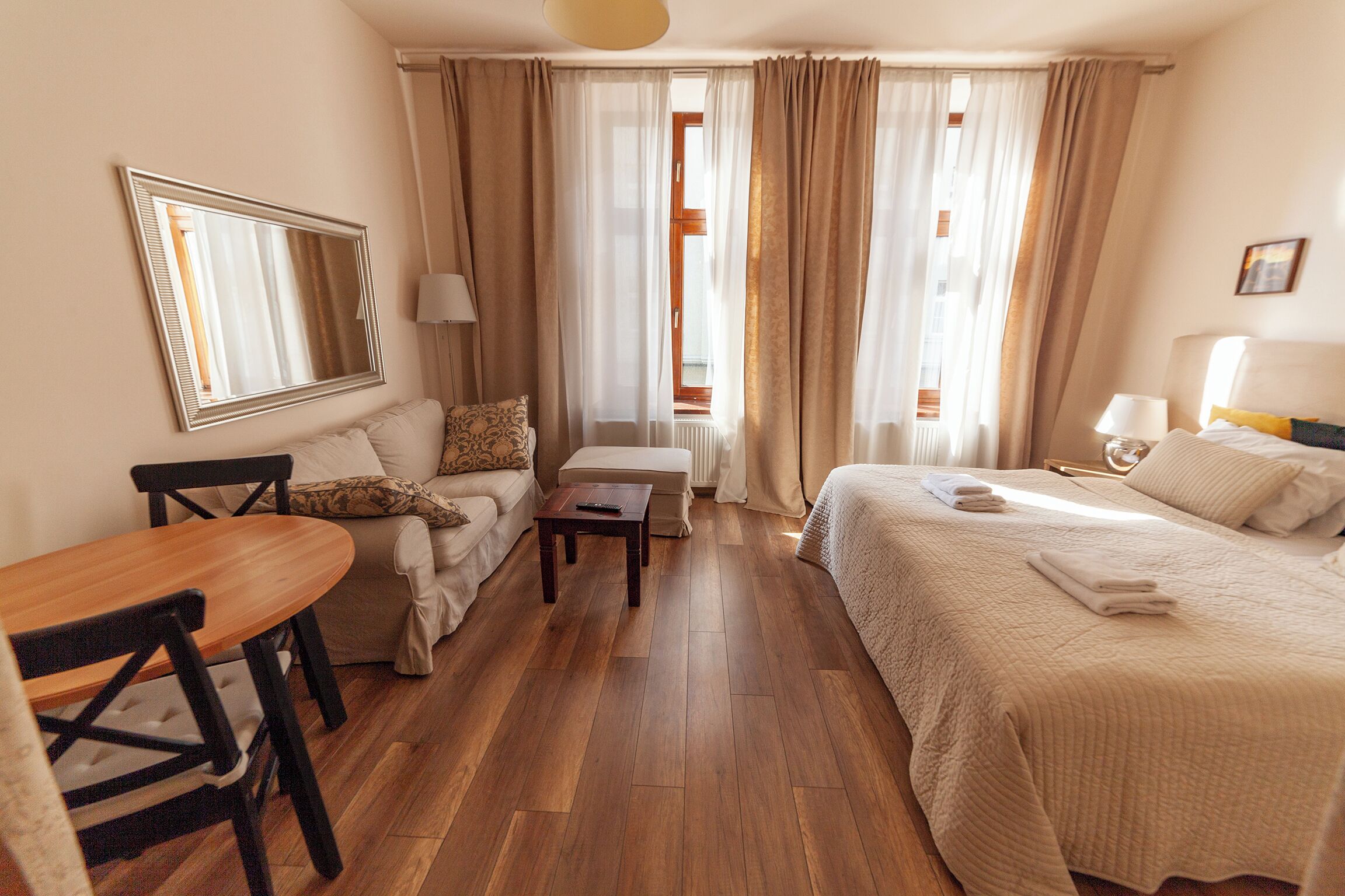 A hotel room with a bed, a sofa, a table, and a chair.