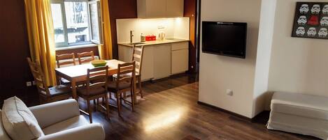 Un espacio habitable compacto con comedor, kitchenette y zona de estar.