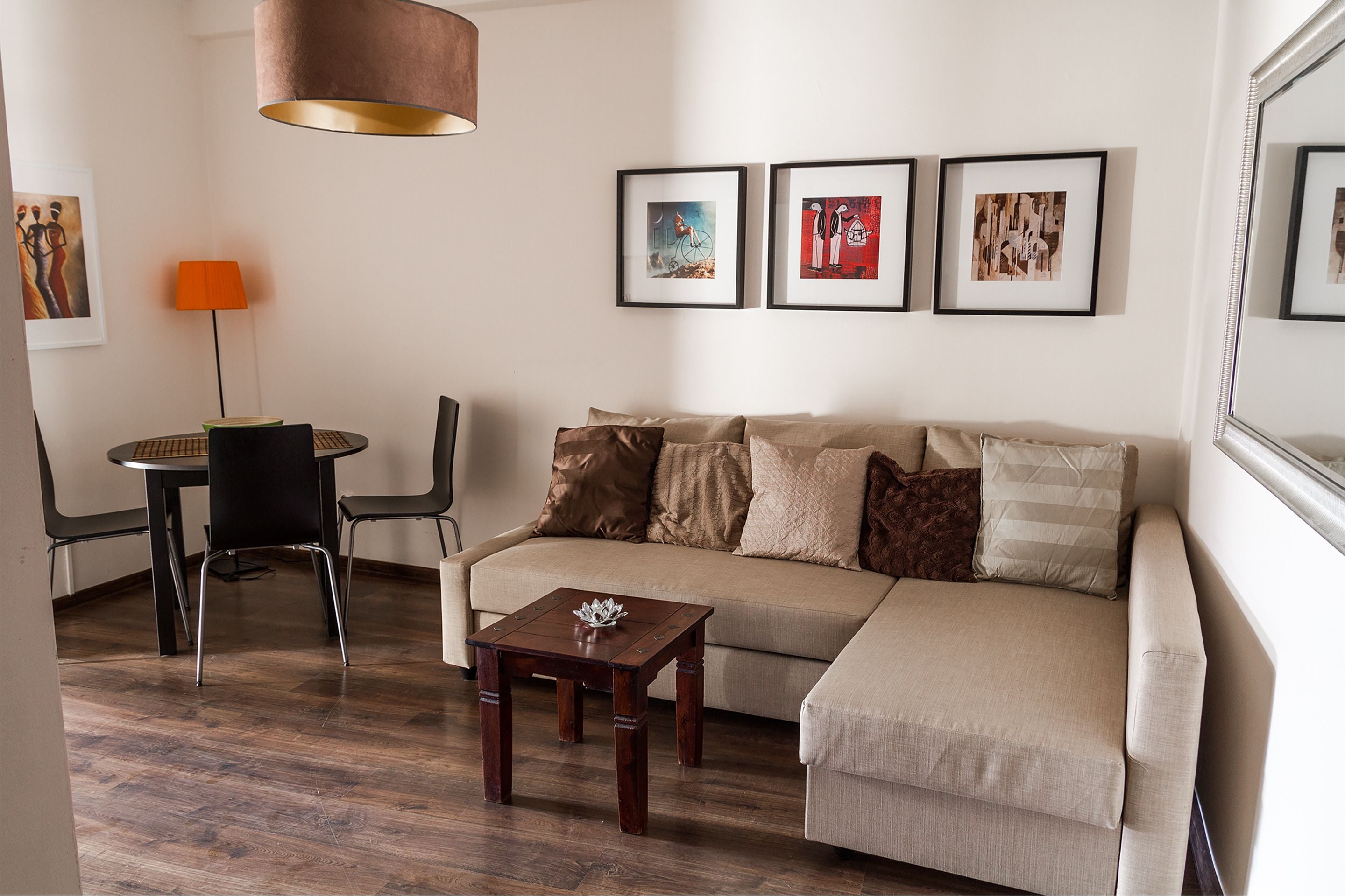 Ein Wohnzimmer mit einer Couch, einem Couchtisch, einem Esstisch mit Stühlen und gerahmten Kunstwerken an der Wand.