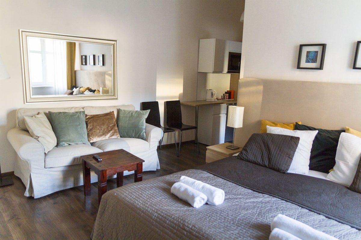 A hotel room with a bed, a sofa, a desk, and a chair.