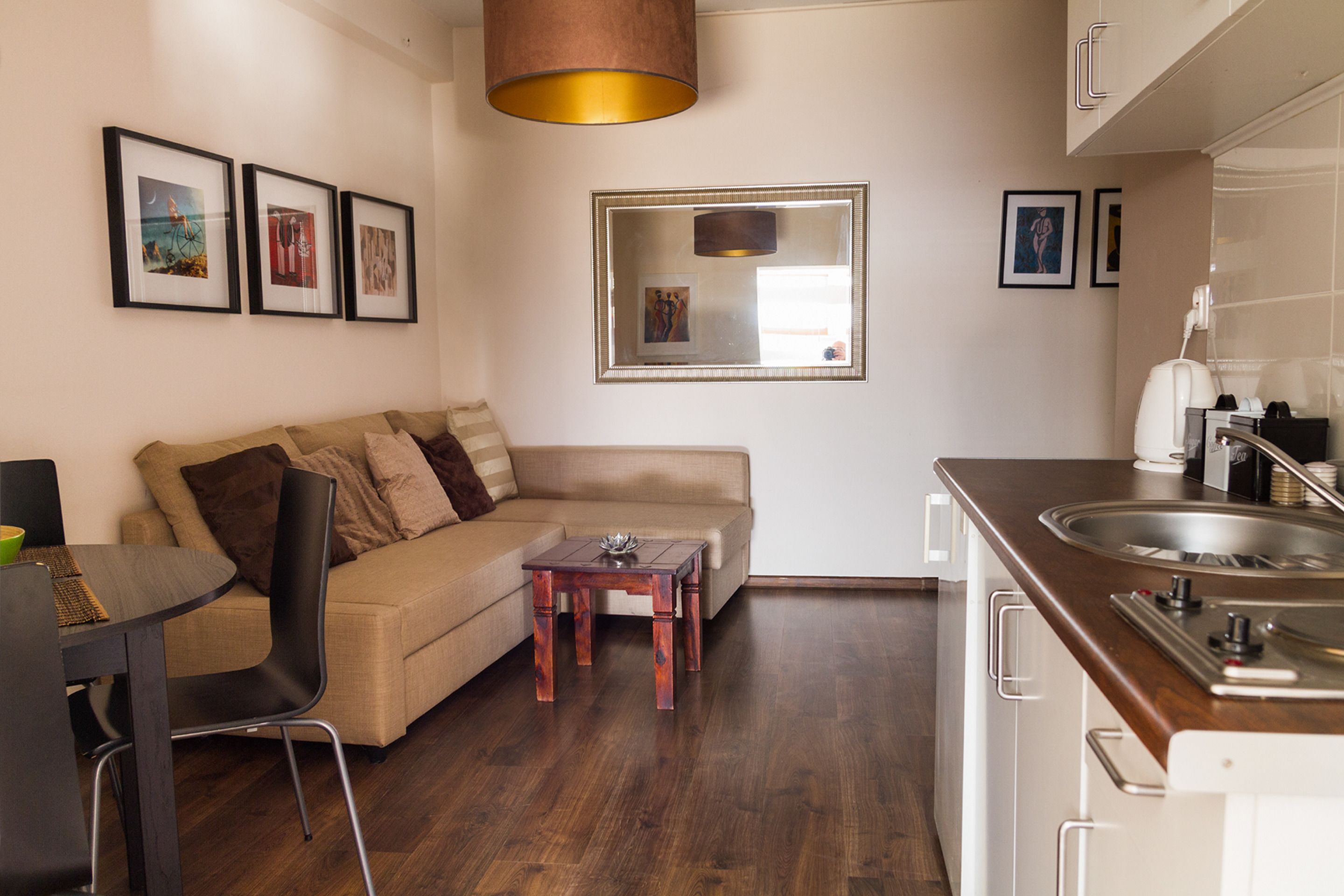 A modern living room with a sofa, a dining table, and a kitchen area with a sink and cabinets.