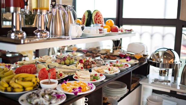 A buffet with various fruits, sandwiches, and beverages. - Golden Moon Suite Hotel (Hanoi)