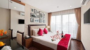 A hotel room with a bed, bedside table, mirror, and a TV on the wall. - Golden Moon Suite Hotel (Hanoi)