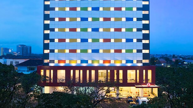 A modern hotel with a distinctive multicolored facade and a lower section with large windows. - Amaris Hotel Pettarani Makassar (Makassar)