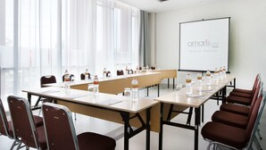 A conference room with a long table, chairs, water bottles, and a projector screen displaying the hotel name. - Amaris Hotel Pettarani Makassar (Makassar)