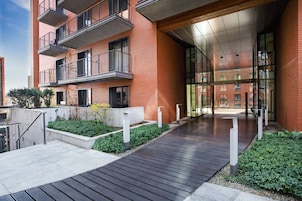 Un bâtiment moderne avec une façade en briques, une terrasse en bois et une entrée en verre.
