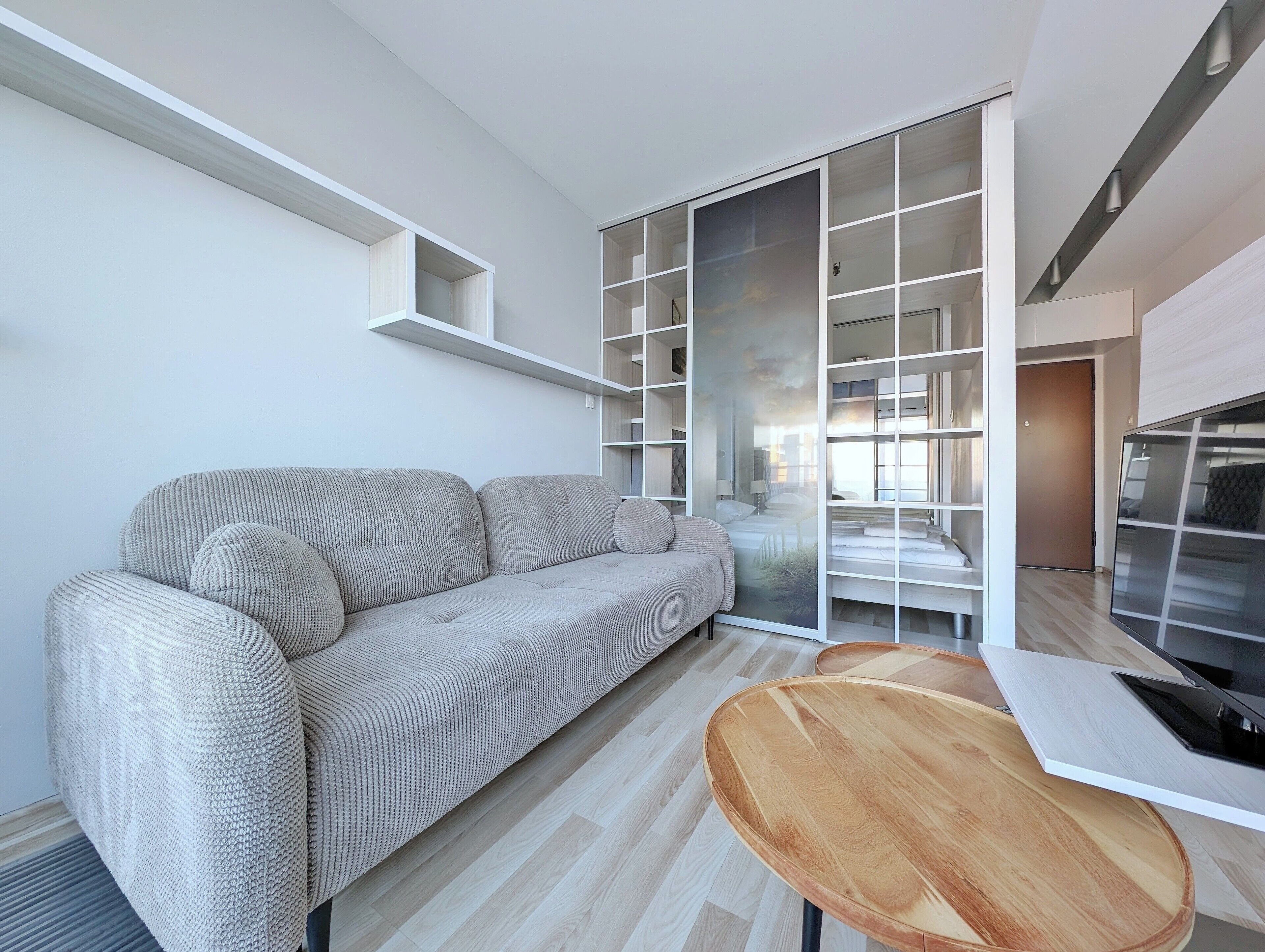A modern living room with a sofa, a wooden table, and built-in shelving.