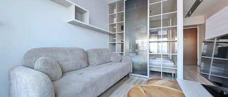 A modern living room with a sofa, a wooden table, and built-in shelving.