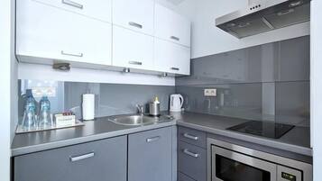 A modern kitchen with grey cabinets, stainless steel appliances, and a wooden floor.