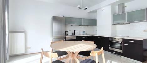 A modern kitchen with a dining area, featuring a round table, wooden chairs, and built-in appliances.