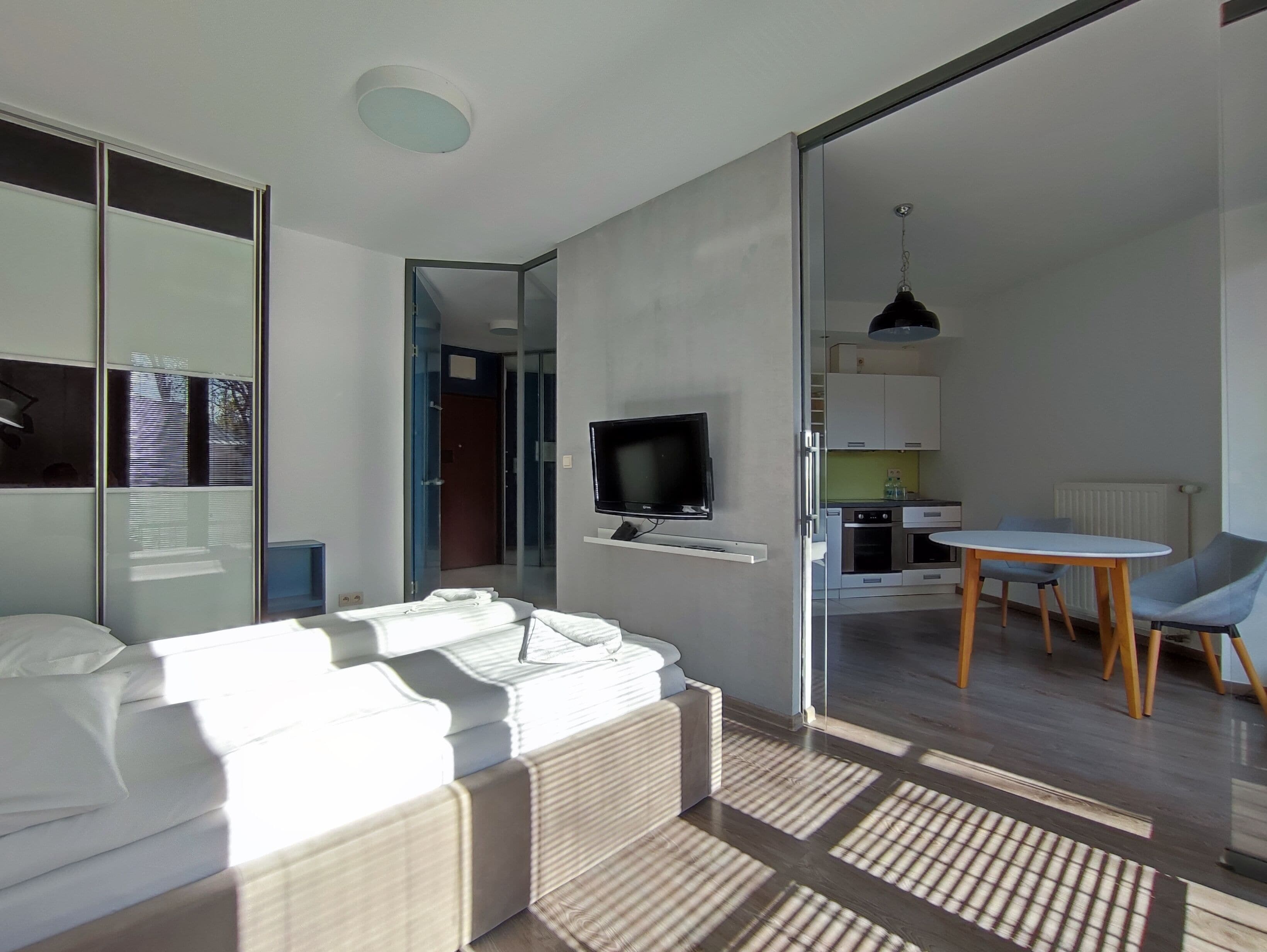 A modern living room with a sofa, a television, and a dining area with a table and chairs.