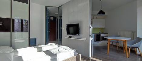 A modern living room with a sofa, a television, and a dining area with a table and chairs.