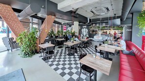 A modern cafe with checkered flooring, black and white striped chairs, and a red sofa.