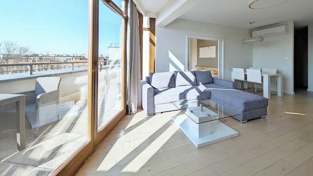 A modern living room with a sofa, a glass coffee table, and a dining area with chairs.