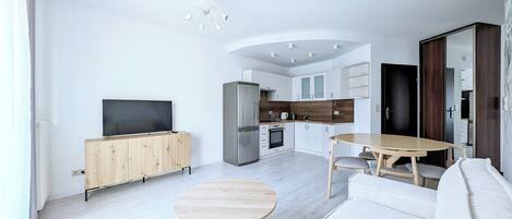 A modern living room with a flat-screen TV, wooden cabinet, round coffee table, and a sofa.