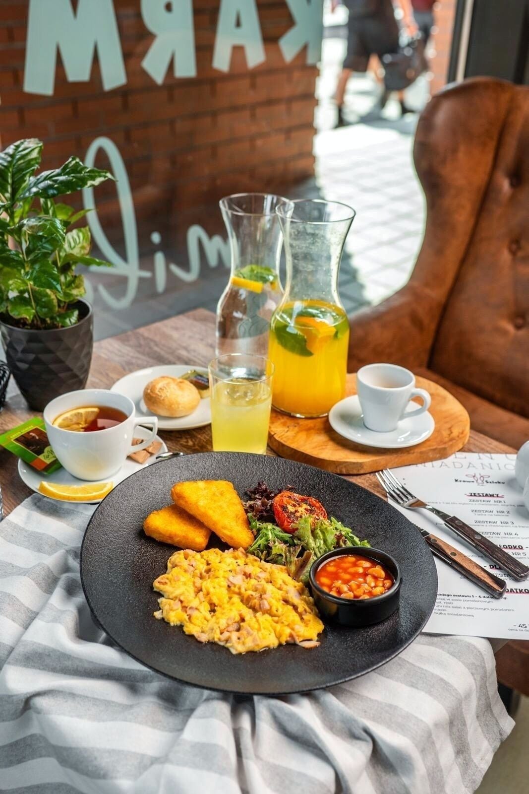 A breakfast setting with scrambled eggs, toast, a salad, and a pitcher of orange juice.