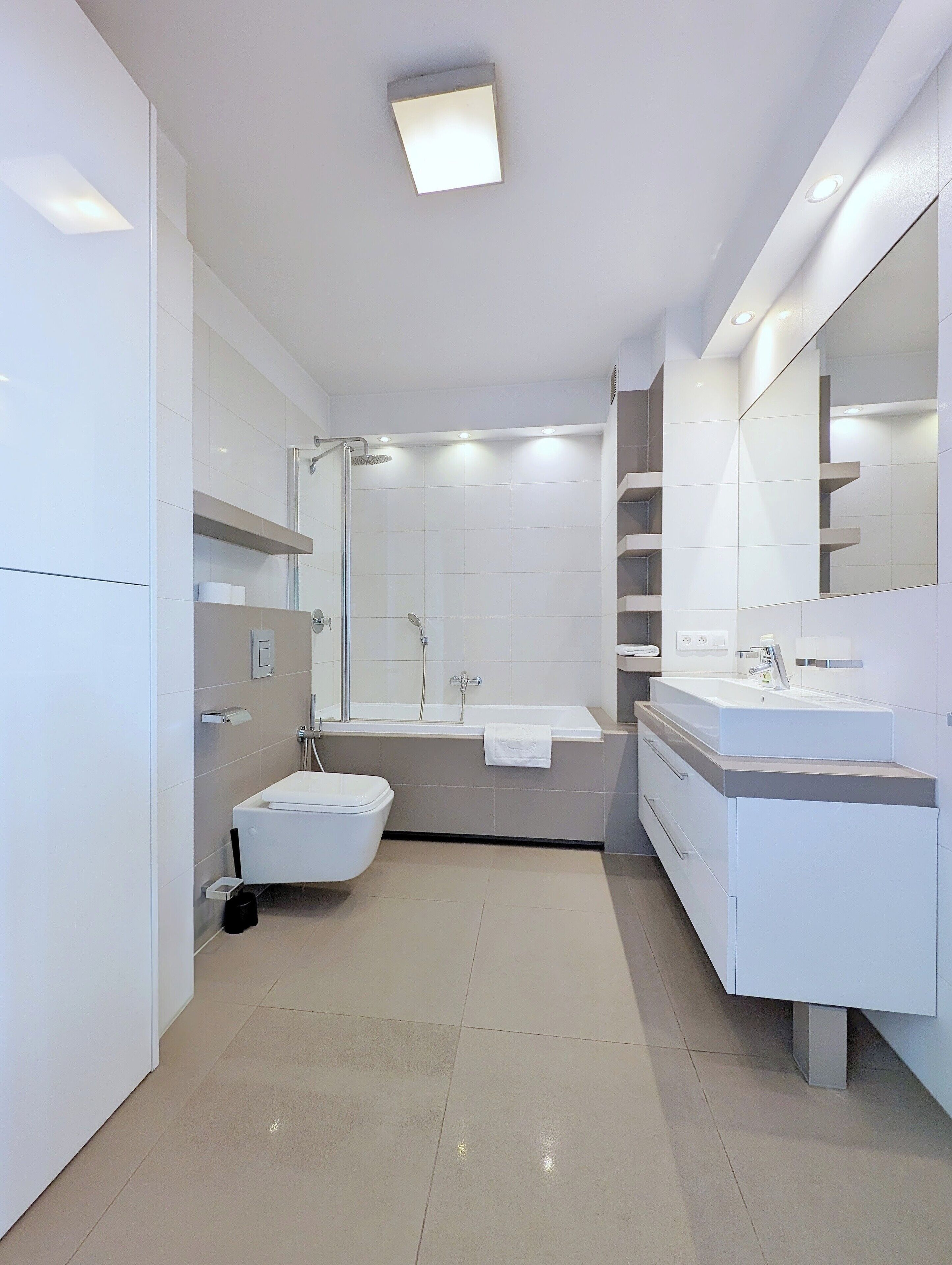 A modern bathroom with a freestanding bathtub, a separate toilet, and a vanity with a large mirror.