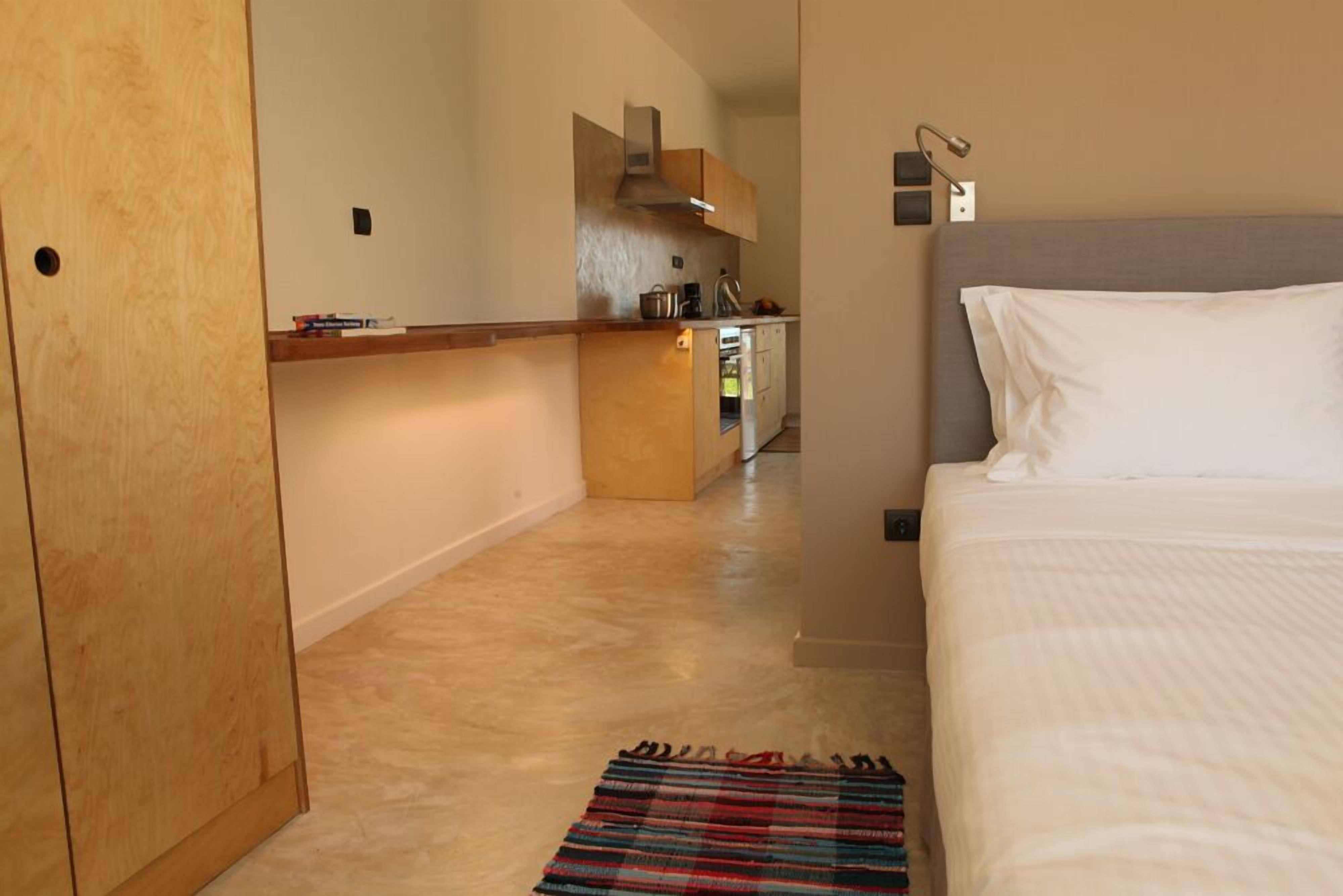 Habitación de hotel con cama, una kitchenette pequeña y un armario de madera.