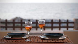 Uma mesa com dois copos de líquido âmbar e duas tigelas, com vista para o mar.