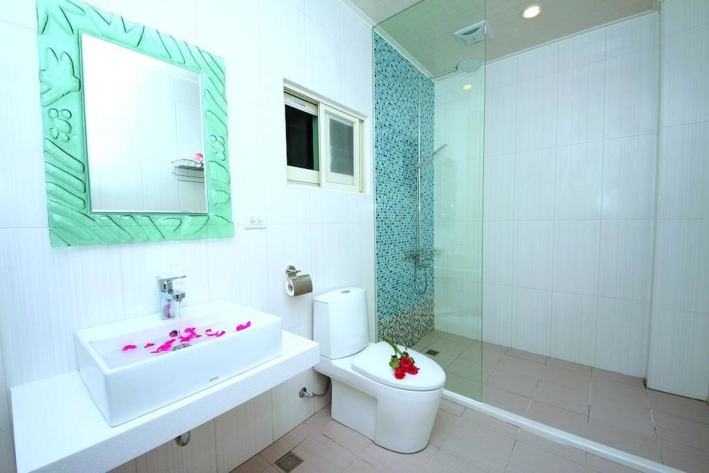 A modern bathroom with a white sink, a toilet, and a glass shower enclosure.
