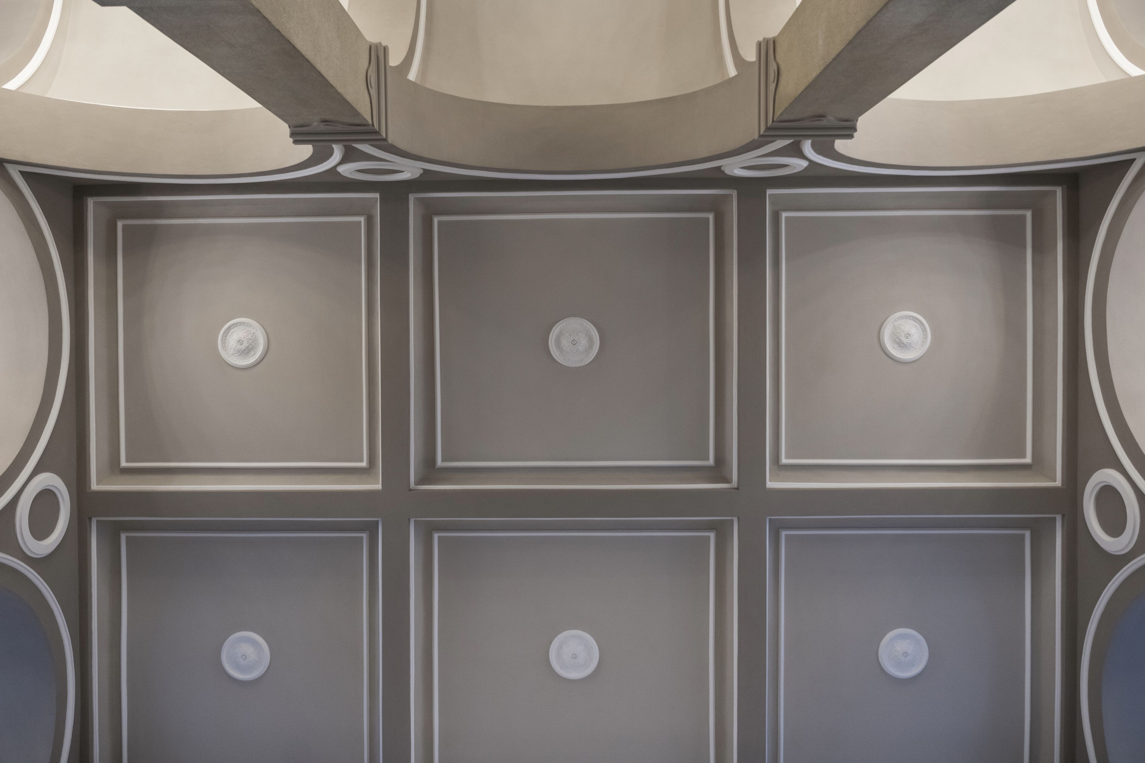 A ceiling with a symmetrical design featuring recessed lighting and decorative moldings.