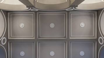 A ceiling with a symmetrical design featuring recessed lighting and decorative moldings.