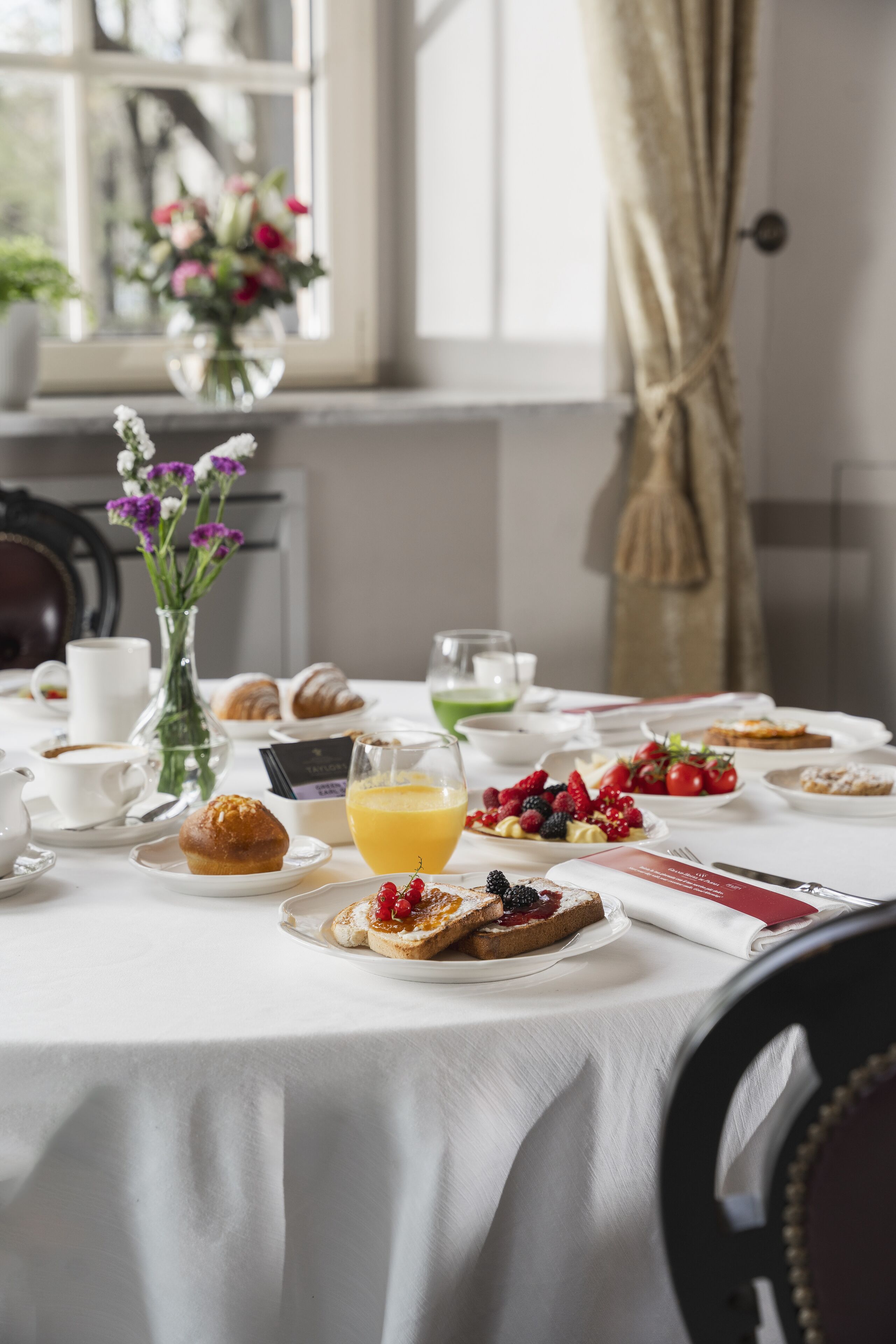 A breakfast table set with croissants, pastries, fresh berries, and orange juice.