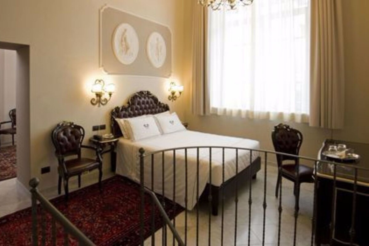 A hotel room with a bed, a desk, a chair, a small table, and a window with curtains.