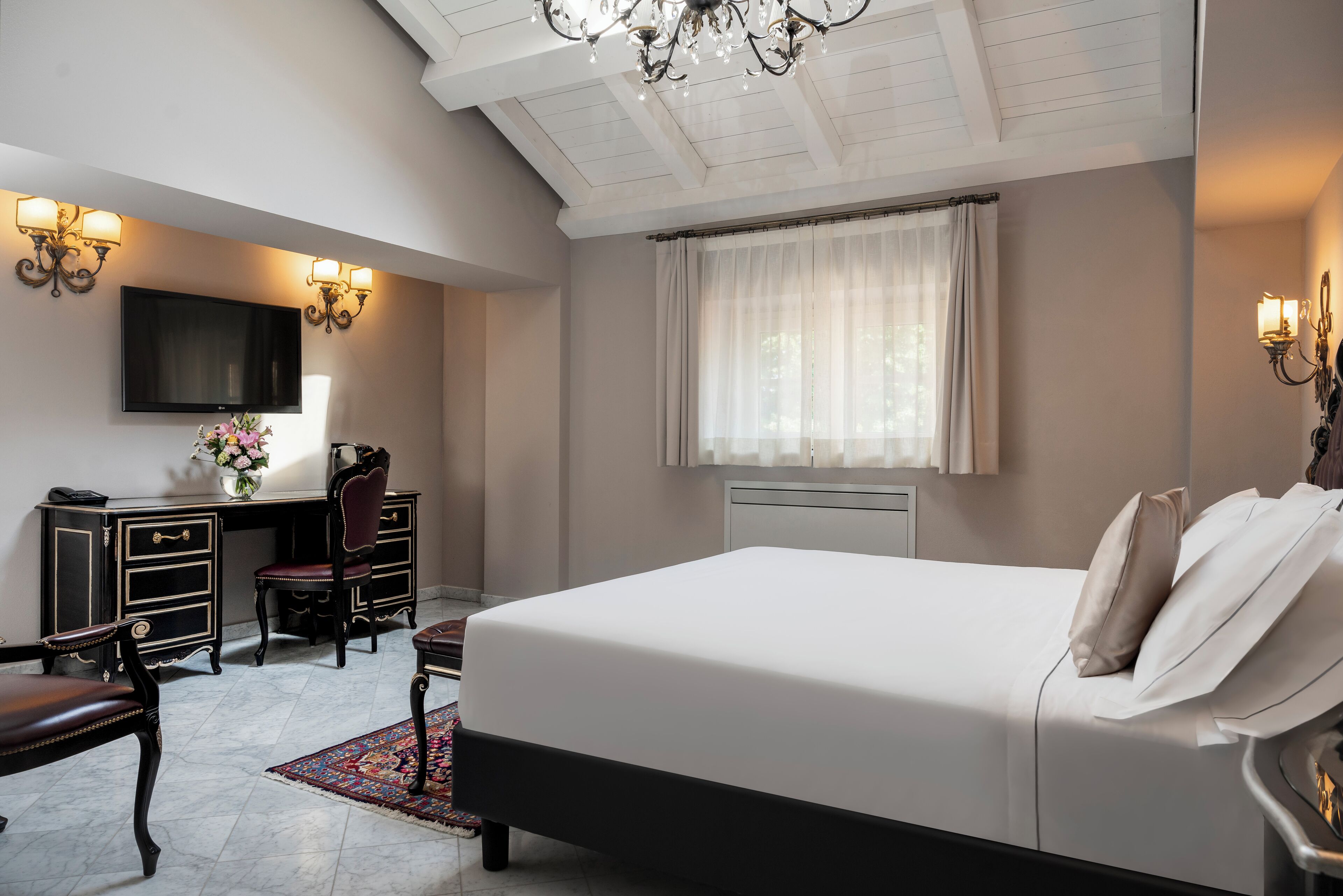 A bedroom with a large bed, a desk, a chair, and a television.