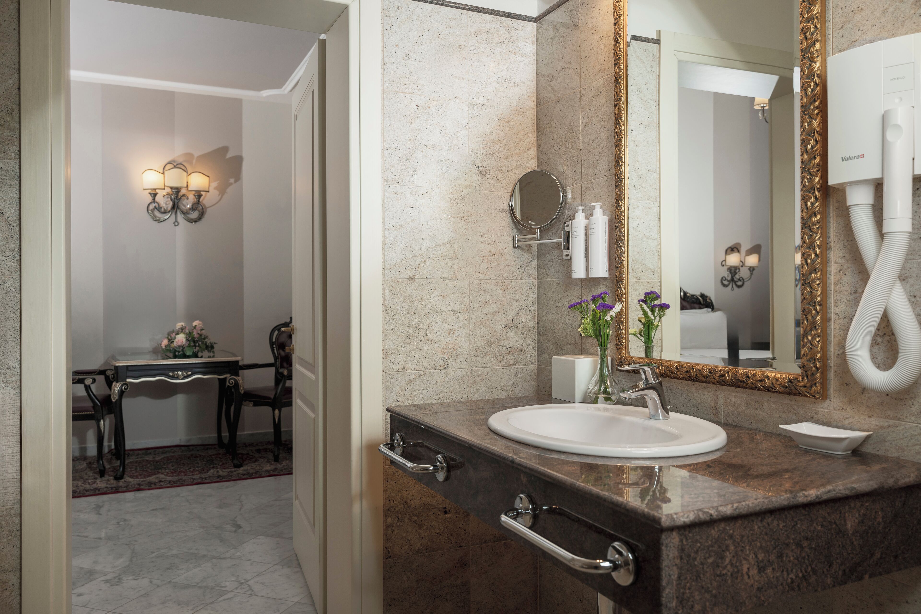 Un bagno con lavabo in marmo, una cassettiera con specchio e un asciugacapelli.
