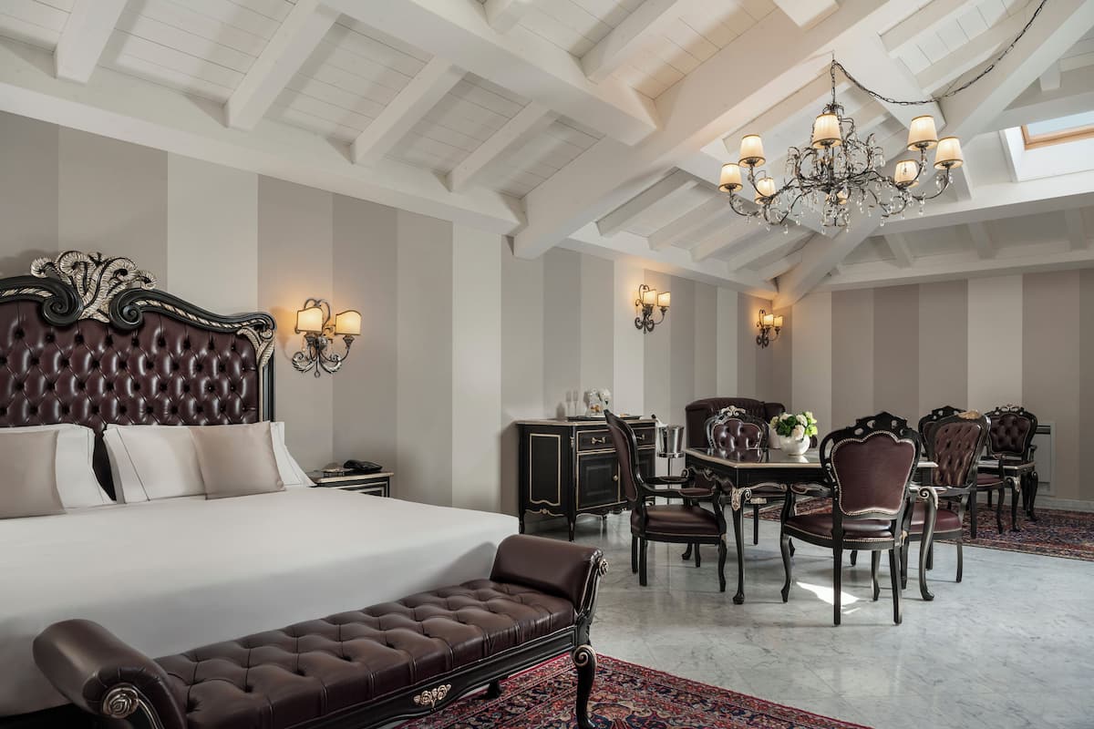 Une chambre spacieuse avec un grand lit, un coin salon et un coin repas équipé de plusieurs chaises.