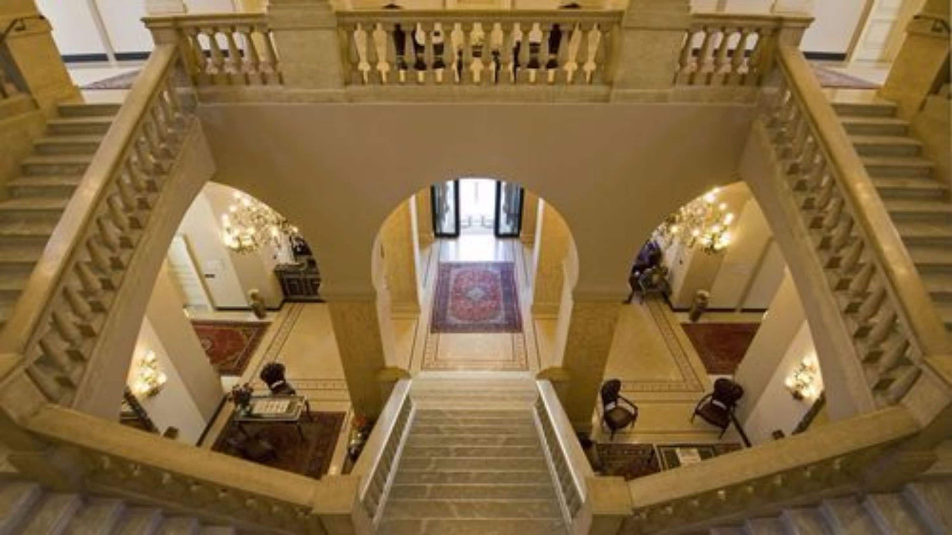 A grand staircase with a central landing, flanked by two balconies with railings.