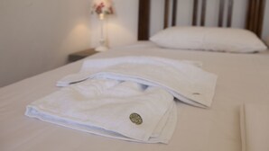 A neatly made bed with white linens and pillows, a bedside lamp, and a wooden headboard. - Horizonte Cretan Cottage (Kissamos)