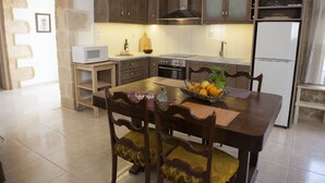 A modern kitchen with wooden cabinets, a microwave, a stove, and a refrigerator. - Horizonte Cretan Cottage (Kissamos)