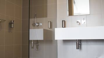 Un baño moderno con cabina de ducha de vidrio, un lavabo blanco y un espejo encima.