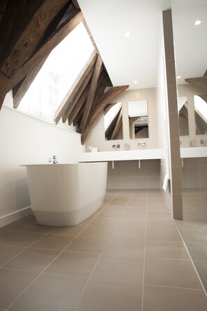 A modern bathroom with a freestanding bathtub, a vanity with a mirror, and a skylight. - Hotel & Brasserie Katoen (Goes)