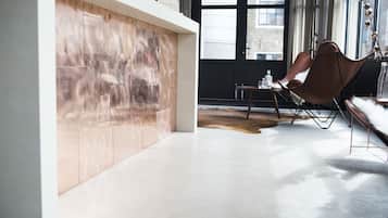 Un intérieur moderne avec un mur en bois, un coin salon avec un fauteuil et une vue dégagée sur l’extérieur grâce à de grandes fenêtres.