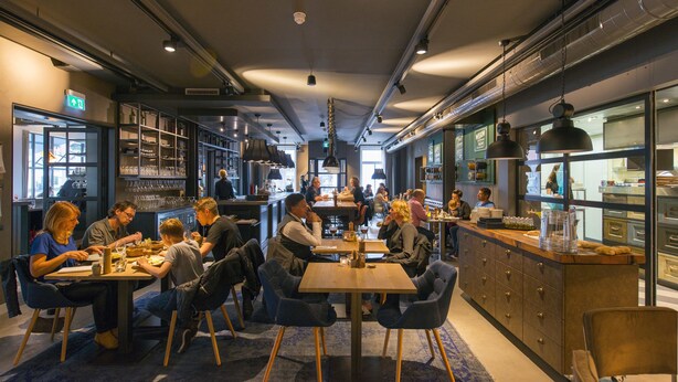 A modern restaurant with a bar area, dining tables, and chairs. - Hotel & Brasserie Katoen (Goes)