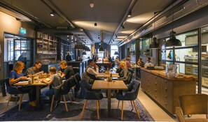 Un restaurant moderne doté d’un bar, de tables et de chaises.