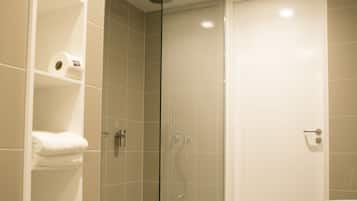 Un baño moderno con ducha de vidrio, bañera blanca y estante con toallas.